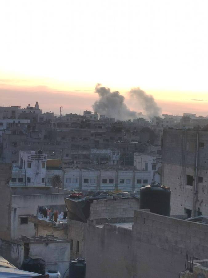 A landscape of a destroyed area in Gaza with smoke and fire