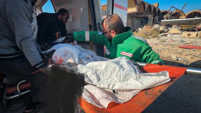 A medical worker putting the body of a martyr into the back of an ambulance, after a bombing